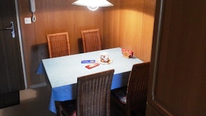 A dining area with a table, chairs, a hanging light fixture, and a wall-mounted telephone. - Golfpark B 14 Appartement/Fewo, Dusche oder Bad, WC 1½-Zimmerwohnung by Interhome (Davos)