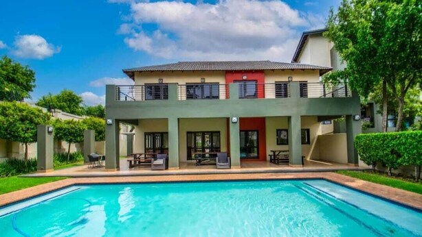 A two-story building with a swimming pool in front. - Stylish Studio Apartment In Fourways (Sandton)