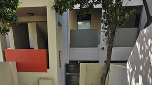 A courtyard with a grassy area, a tree, and a red wall. - Stylish Studio Apartment In Fourways (Sandton)