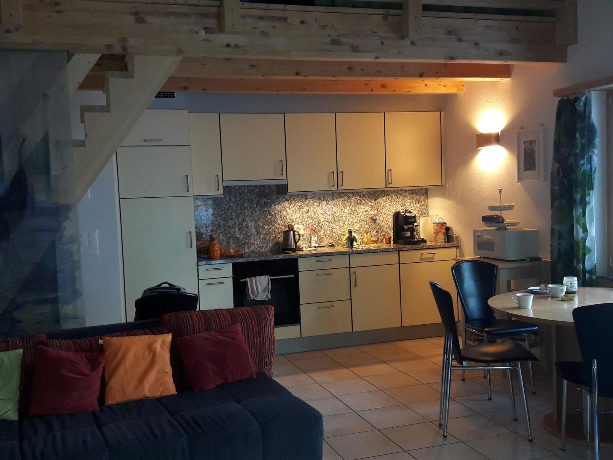 Une cuisine compacte avec des meubles blancs, un plan de travail en granit et un coin repas comprenant une table et des chaises.