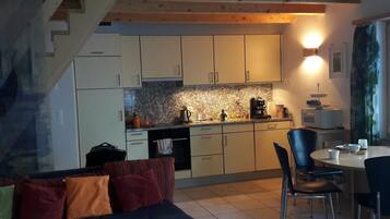 Une cuisine compacte avec des meubles blancs, un plan de travail en granit et un coin repas comprenant une table et des chaises.