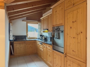 Eine Küche mit Holzausstattung, einem Edelstahlbackofen und einem Fenster mit Blick ins Freie.