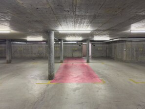 Eine Tiefgarage mit Betonpfeilern, einem roten Teppich und gelben Linien auf dem Boden.
