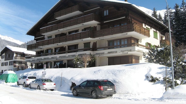 A multi-story hotel with balconies, a parking area, and snow-covered surroundings.