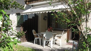A patio with a table and chairs, a wooden fence, and a building with a white exterior.