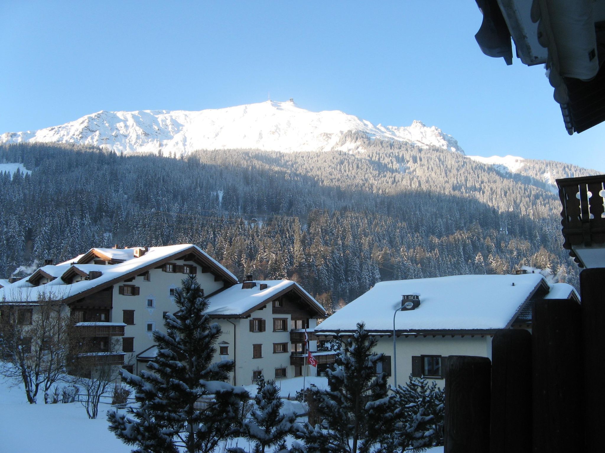 Ein schneebedeckter Berg mit einem Chalet im Vordergrund.