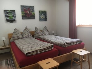 A double bed with striped bedding, a wooden nightstand with a lamp, and three framed pictures on the wall. - Am Bildweg (Stahel) Appartement/Fewo, Dusche oder Bad, WC 2½-Zimmerwohnung by Interhome (Klosters)