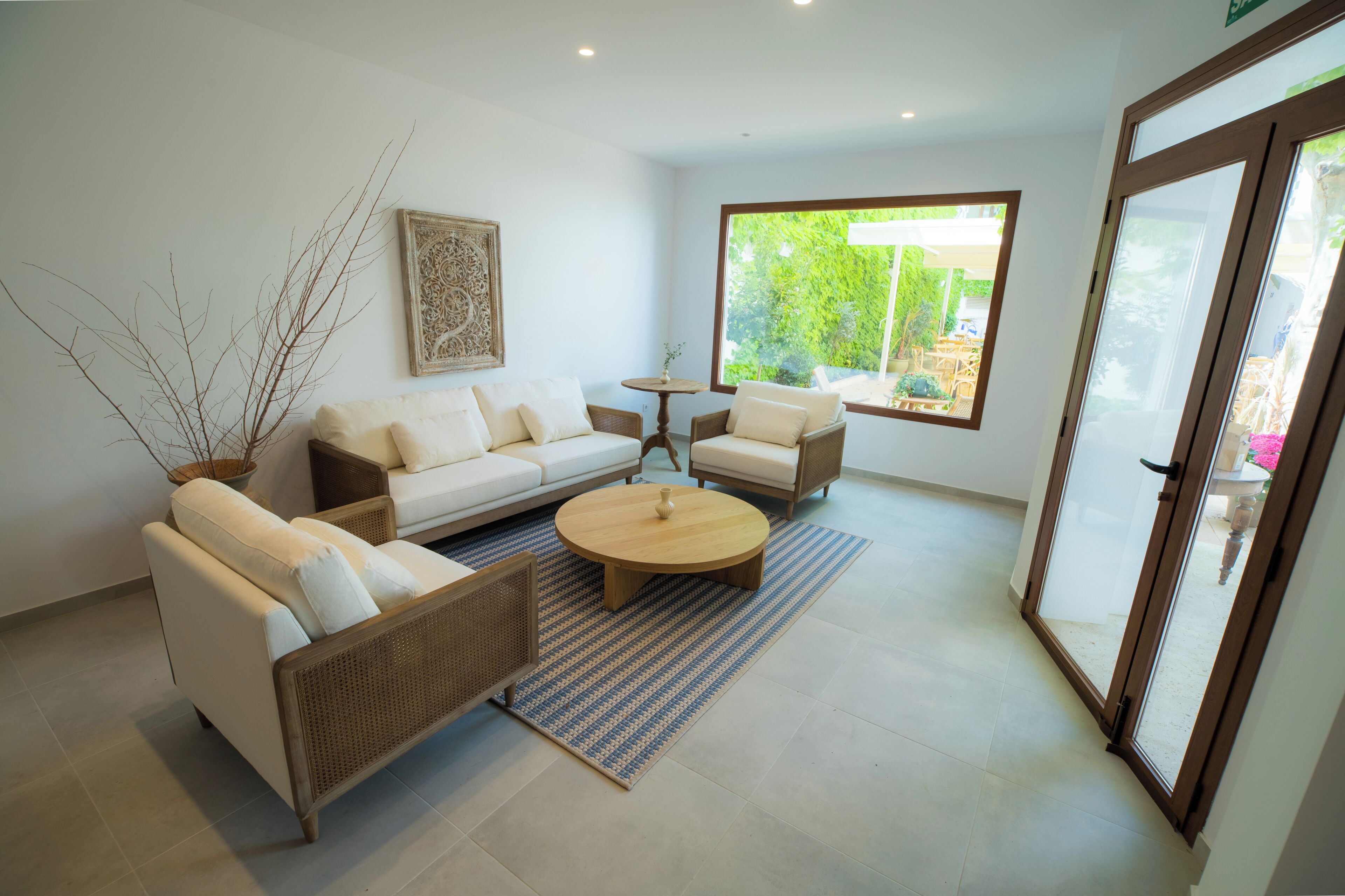 Una sala de estar moderna con un sofá, sillones, una mesita de centro y un ventanal con vistas a zonas verdes.