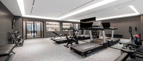 A modern gym with treadmills, elliptical machines, and weight benches.
