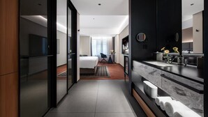 A modern hotel room with a bed, a desk, a bathroom with a mirror, and a TV. - Intercity Hotel Guangzhou Chimelong Wanbo Sihai City (Guangzhou)