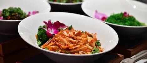 A variety of dishes in bowls, some garnished with flowers, on a wooden table.