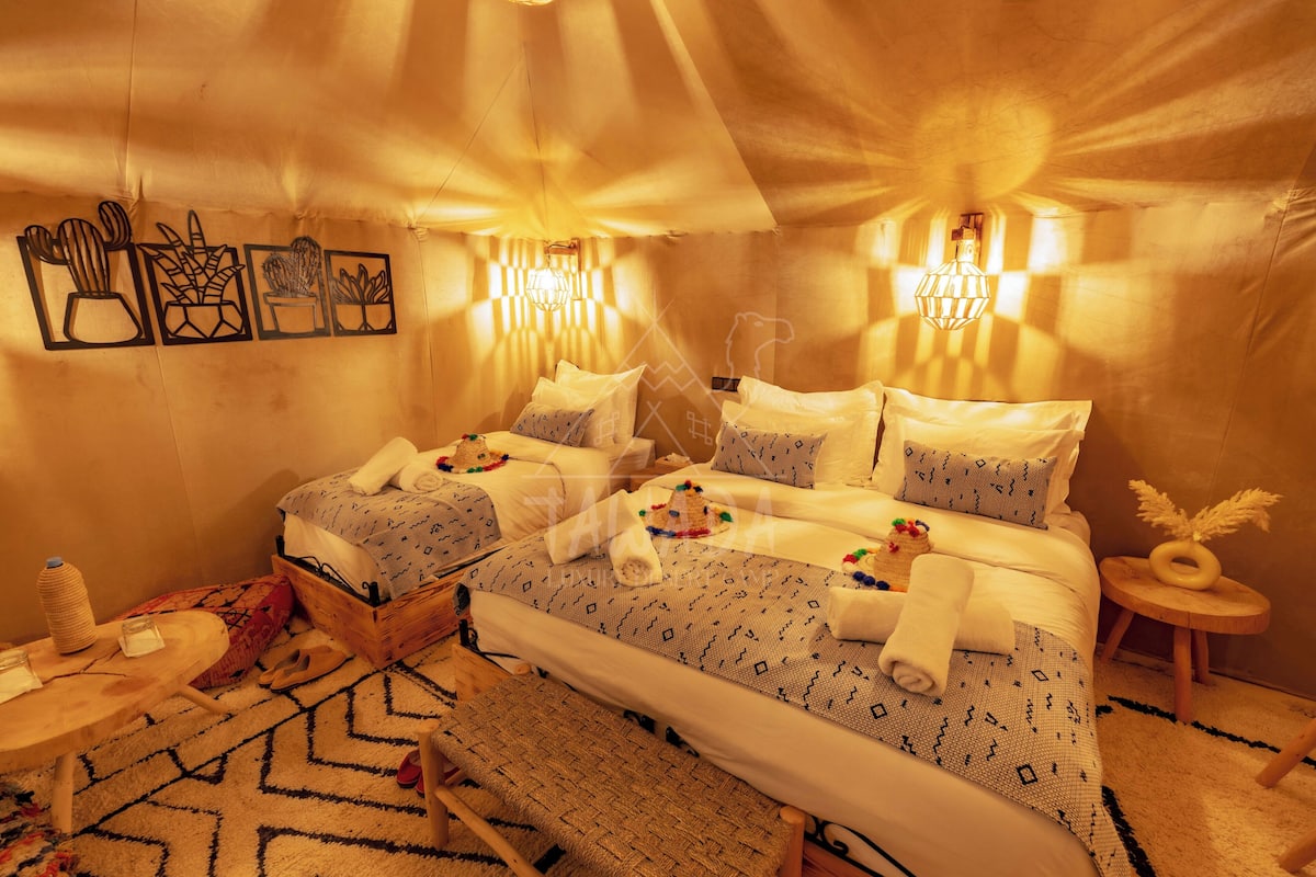 Una habitación acogedora con cama, mesitas de noche, una pequeña mesa redonda y decoración en la pared.