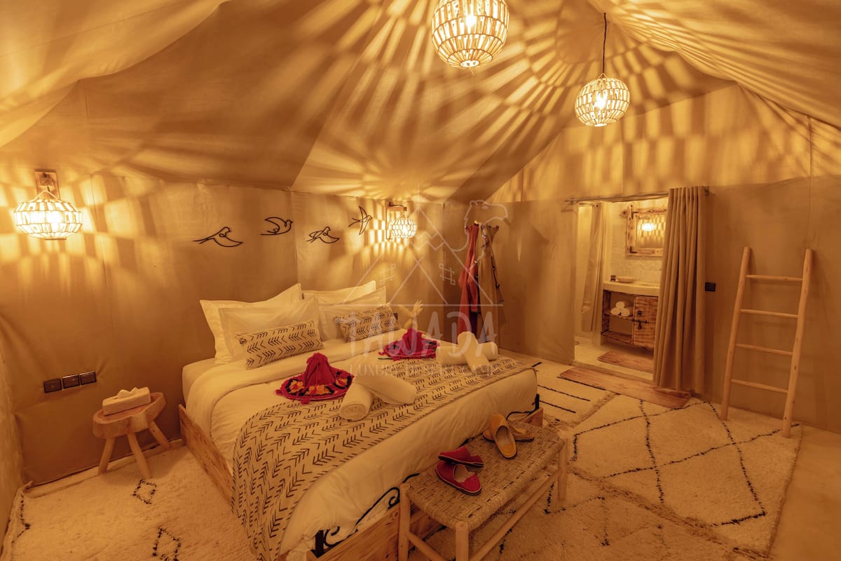 Una habitación con carpa, una cama, un taburete pequeño, un banco y una escalera.