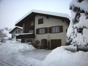 A multi-story building with a sloped roof, wooden exterior, and multiple windows.