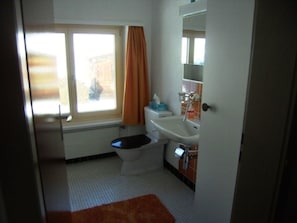 Un baño pequeño con inodoro, lavamanos y ventana.