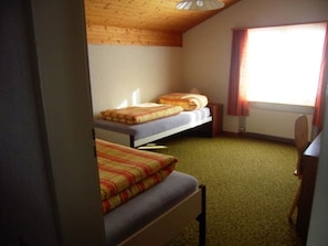 A room with two beds, a window with curtains, and a carpeted floor.