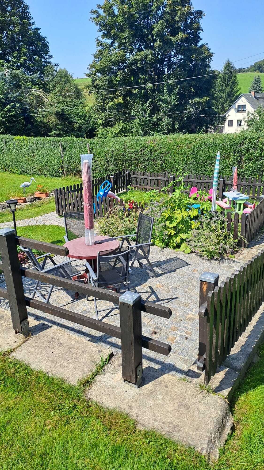 A garden with a picnic table and chairs, surrounded by a wooden fence.