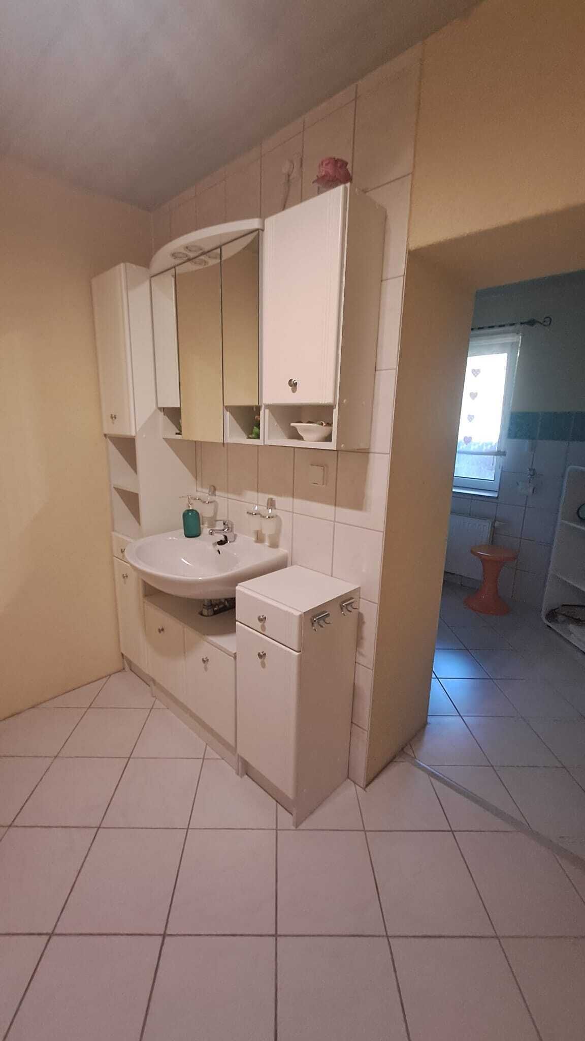 A bathroom with a sink, mirror, cabinets, and a toilet.