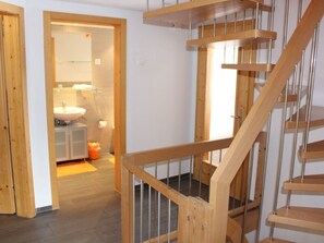 A wooden staircase leading to a bathroom with a sink and mirror.