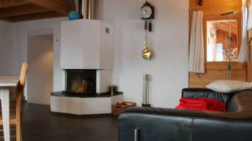 A modern living room with a fireplace, a sofa, and a dining area.