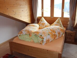 A wooden bed with floral bedding in a room with wooden walls and a window.