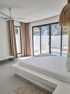 A bedroom with a large bed, a ceiling fan, and a view of a swimming pool.