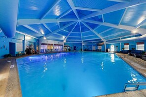 An indoor swimming pool with a blue ceiling and walls, surrounded by seating areas and a poolside bar. - Sleeps 12 • Hot Tub • 5 Min to Lake Beach (Long Pond)