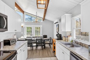 A modern kitchen with white cabinetry, a built-in microwave, and a large window. - Sleeps 12 • Hot Tub • 5 Min to Lake Beach (Long Pond)