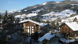 Une station de montagne où les bâtiments sont recouverts de neige et d’où l’on peut admirer un sommet montagneux enneigé.
