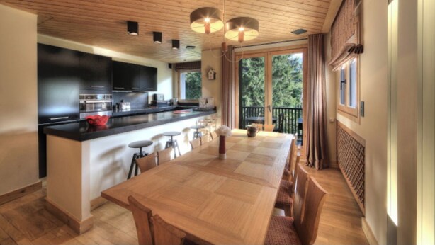 Une cuisine moderne dotée d’un îlot central, de tabourets de bar et d’une table à manger.