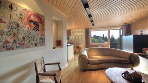 Un salon moderne avec un canapé en cuir, un plafond en bois et un grand tableau abstrait accroché au mur.