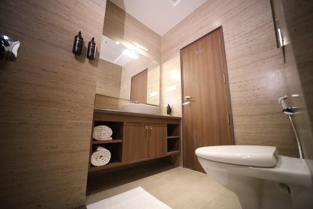 A modern bathroom with a wooden vanity, a large mirror, and a toilet.