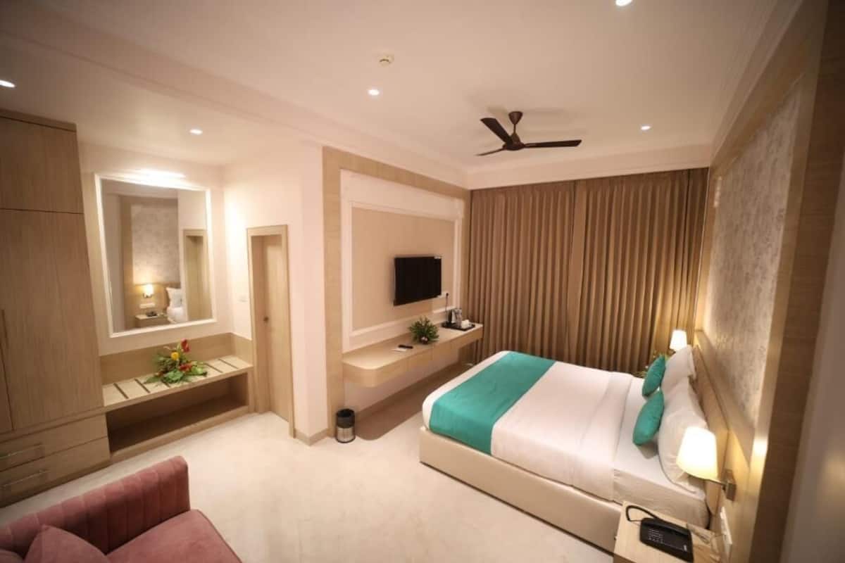 Una habitación de hotel moderna con cama, televisión, escritorio y ventilador de techo.