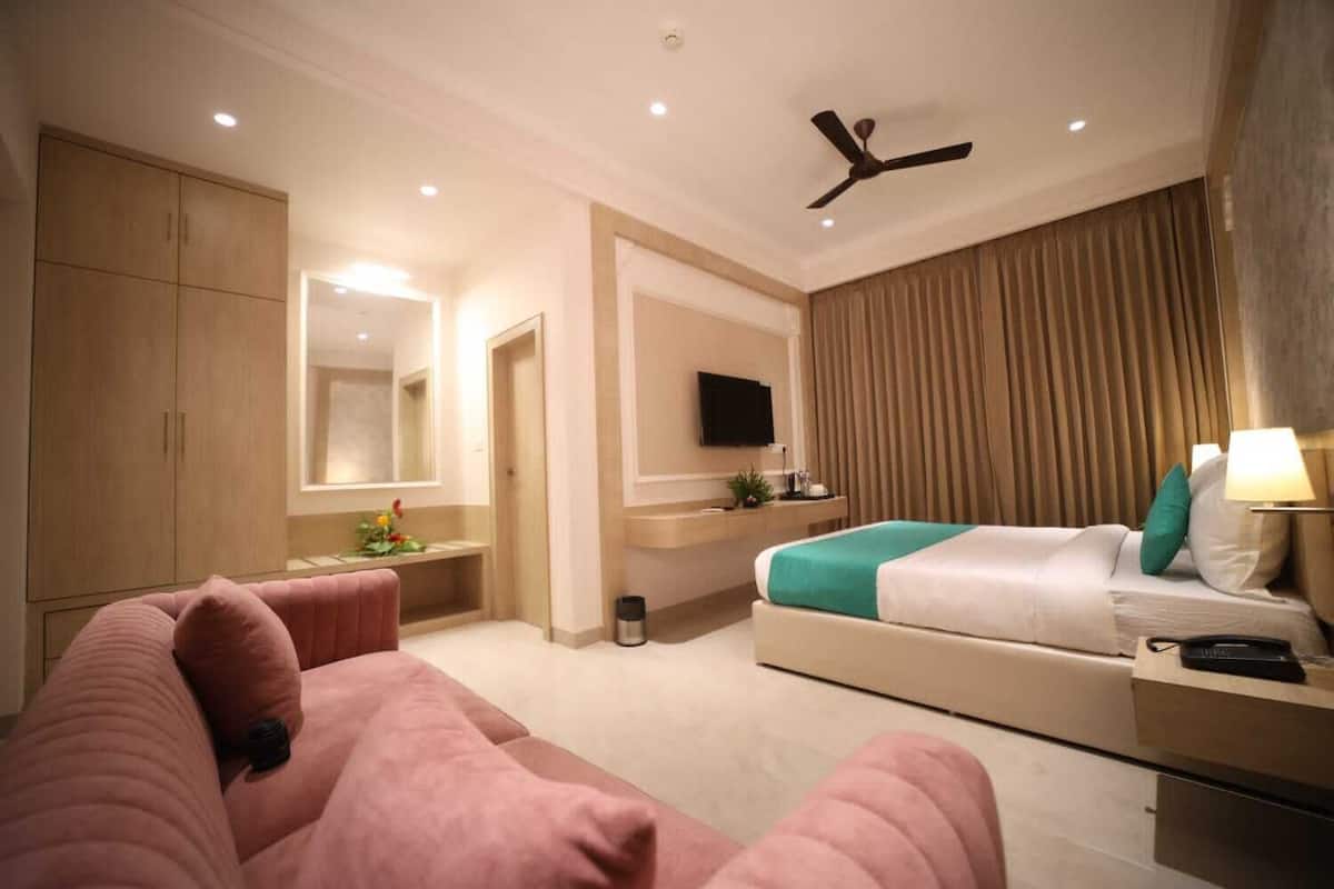 Una habitación de hotel con una cama, un escritorio, una silla, un televisor y un ventilador de techo.