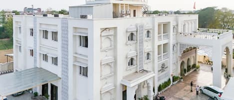A multi-story building with a flat roof, balconies, and a covered entrance area.