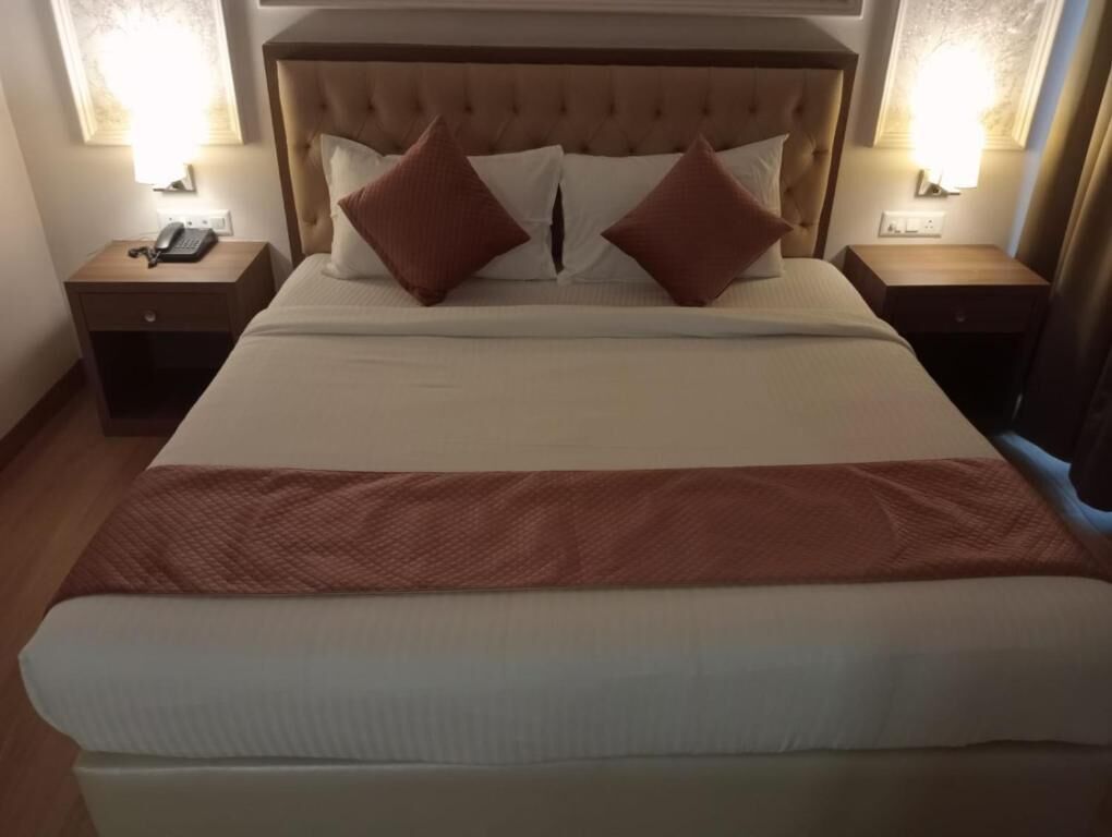 Una habitación de hotel con una cama grande, dos mesitas de noche y un bidet con un teléfono.