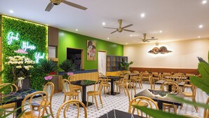 A restaurant with green walls, wooden chairs, and tables. - Golden Sand Phu Quoc Hotel (Phu Quoc)
