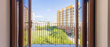 A balcony with patterned floor tiles, a view of multi-story buildings, and a clear sky.