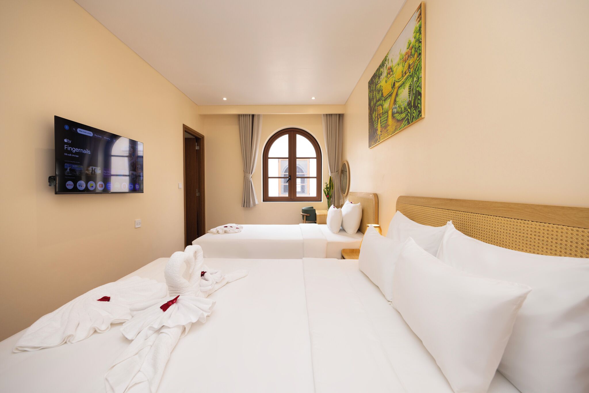 Quarto de hotel com duas camas, uma televisão na parede, um quadro e uma janela com cortinas.