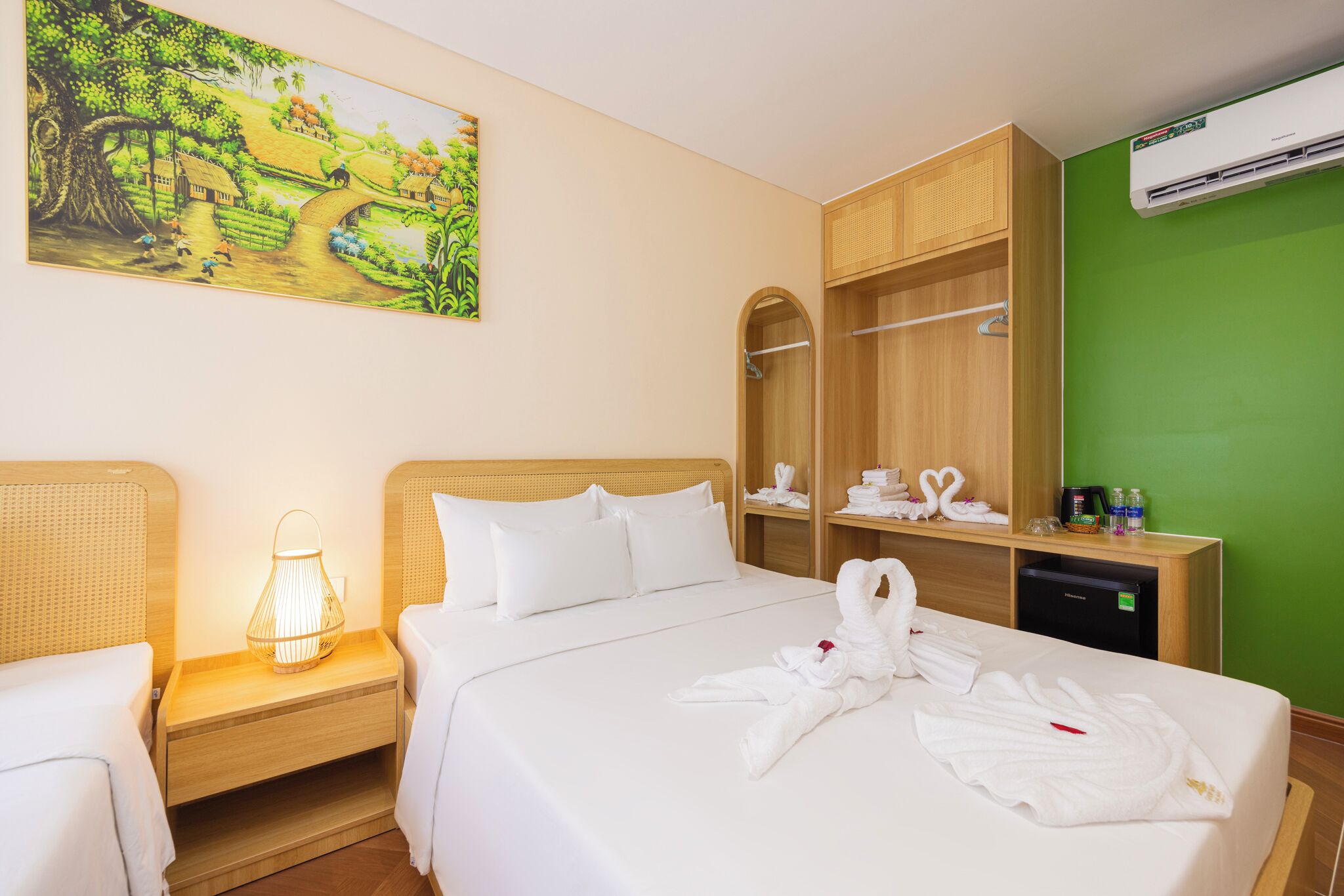 A hotel room with a bed, a nightstand, a lamp, a painting, a wardrobe, and a mirror.