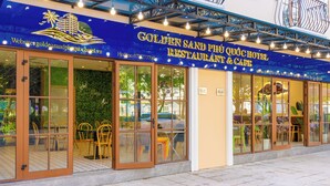 A restaurant with a blue awning, glass doors, and outdoor seating. - Golden Sand Phu Quoc Hotel (Phu Quoc)