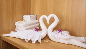 A wooden bench with neatly folded white towels and two towels shaped into swans with purple flowers. - Golden Sand Phu Quoc Hotel (Phu Quoc)