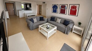 A modern living room with a sofa, coffee table, and kitchen area in the background.