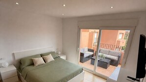 A bedroom with a bed, a nightstand, a TV, and a sliding glass door leading to an outdoor area.