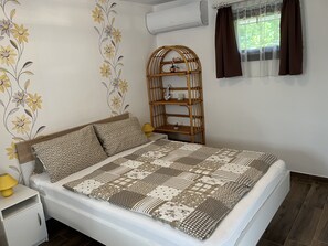 Une chambre à coucher comprenant un lit, une table de chevet, une étagère fixée au mur et une fenêtre avec des rideaux.