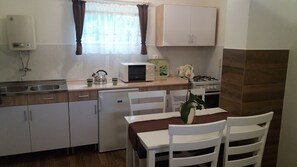 Une cuisine compacte équipée d’un four à micro-ondes, d’une bouilloire, d’un évier et d’une petite table à manger avec des chaises.