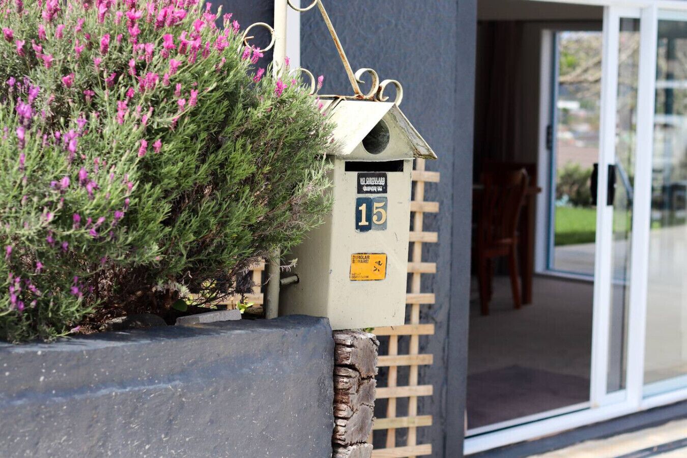 A building entrance with a mailbox, a number '15' sign, and a wooden lattice structure.