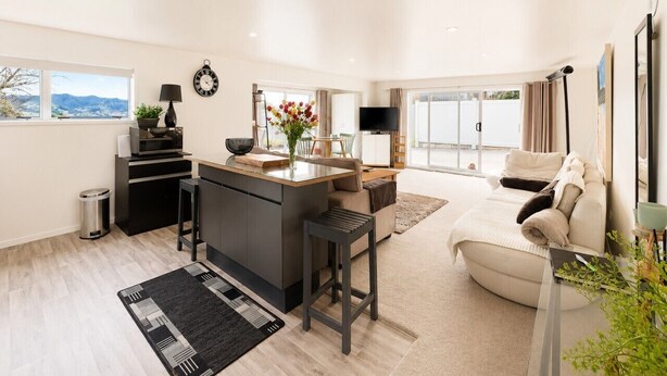 A modern living space with a kitchen island, a sofa, and a TV.