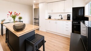 A modern kitchen with white cabinets, a black stove, and a wooden countertop.