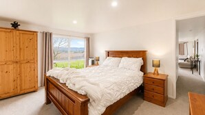 A bedroom with a wooden bed, bedside tables, a wardrobe, and a window with curtains.